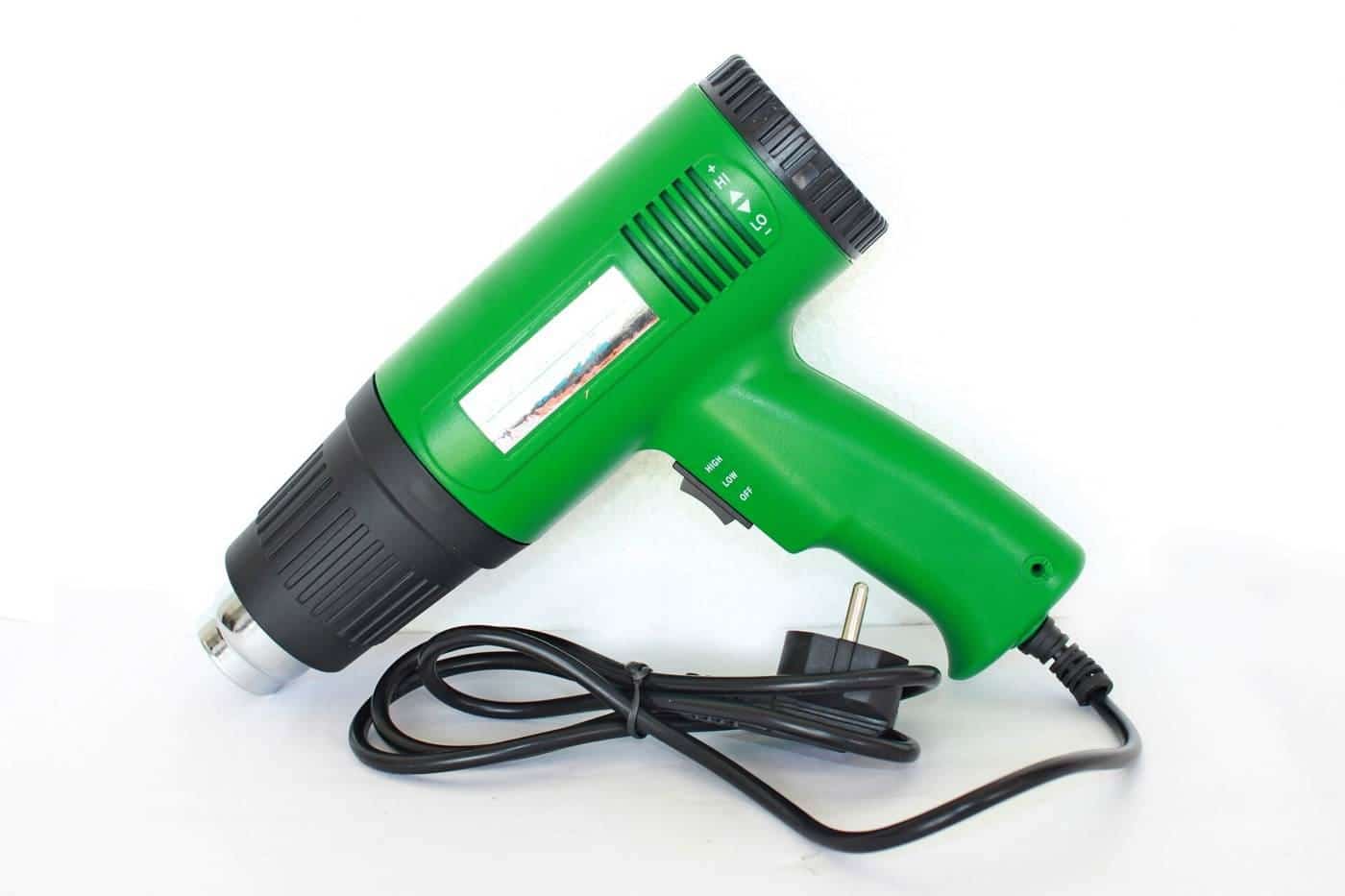 A green handheld hot air gun with its cable on a white background